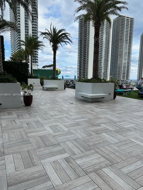 An outdoor patio features gray wood-look tile flooring, palm trees, and modern white planters — 4010 S Ocean Dr # R2702, Hollywood FL 33019, HOLLYWOOD, FL