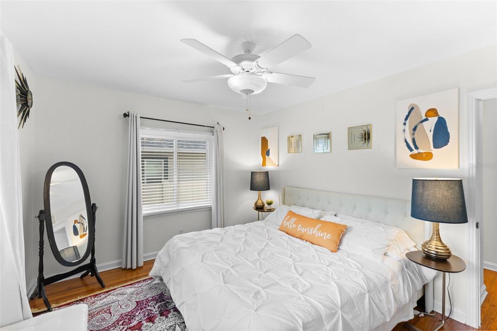 A bedroom features a white bed with a yellow pillow, a ceiling fan, and a mirror — 170 22ND AVENUE N, ST PETERSBURG, FL