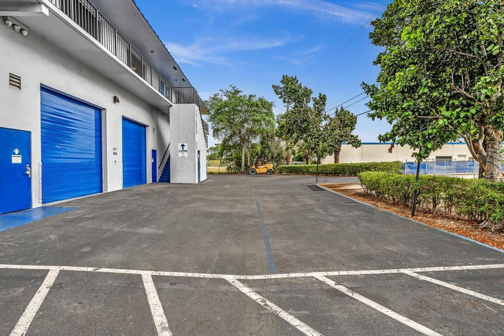 An exterior view of a commercial building with blue roll-up doors and a parking lot — 1150 SW 10th Avenue, Pompano Beach FL 33069, POMPANO BEACH, FL