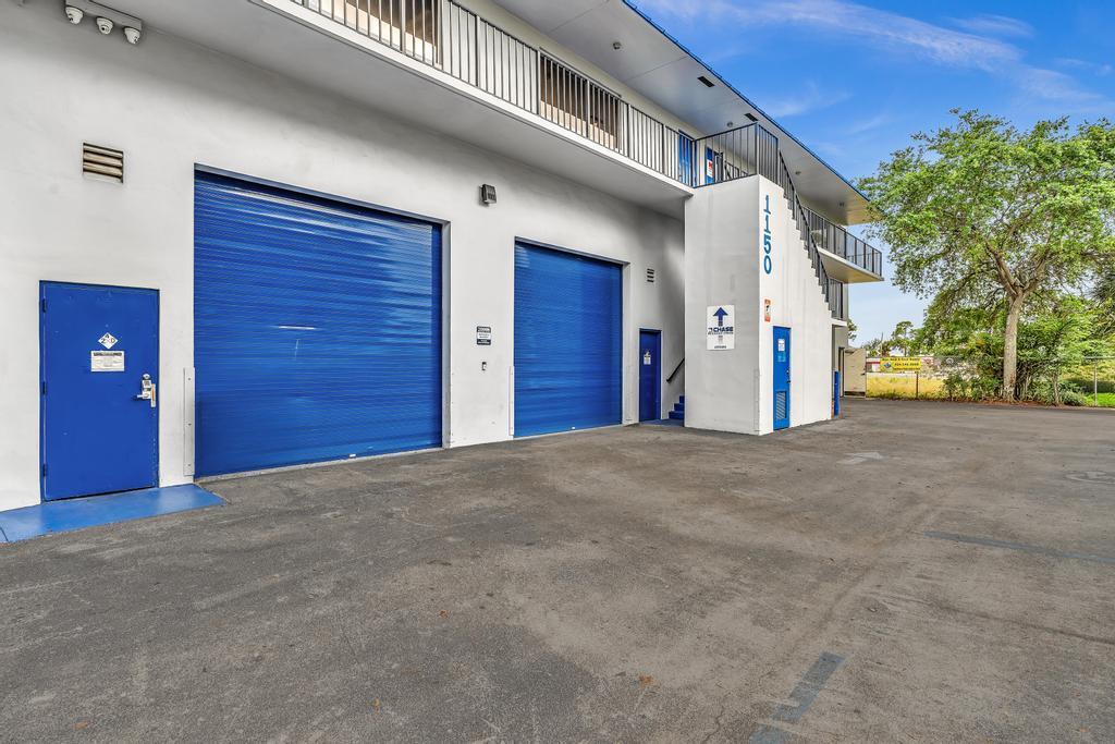 The exterior of a commercial building features two large blue roll-up doors and stairs — 1150 SW 10th Avenue, Pompano Beach FL 33069, POMPANO BEACH, FL