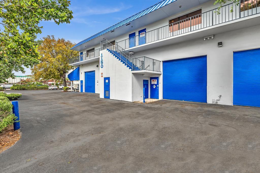 A two-story commercial building features white walls, blue roll-up doors, and an exterior staircase — 1150 SW 10th Avenue, Pompano Beach FL 33069, POMPANO BEACH, FL