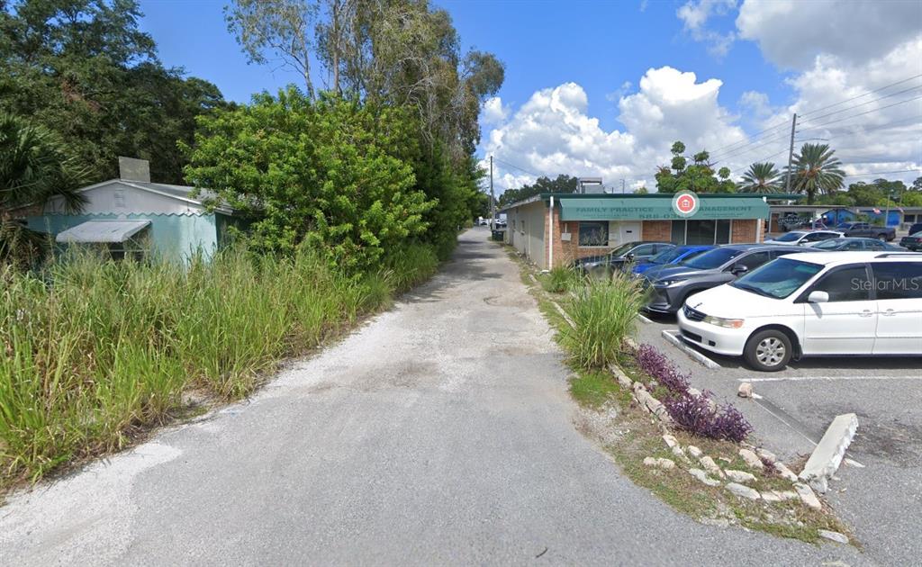 A gravel driveway runs between a small house and a commercial building with parked cars — 101 CLEARWATER-LARGO ROAD, LARGO, FL