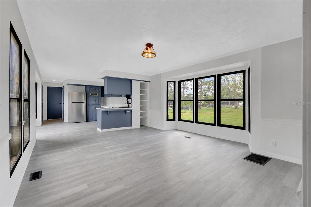 A bright living area with light wood flooring, a blue kitchen island, and large windows — 9185 CONCORD ROAD, ST CLOUD, FL