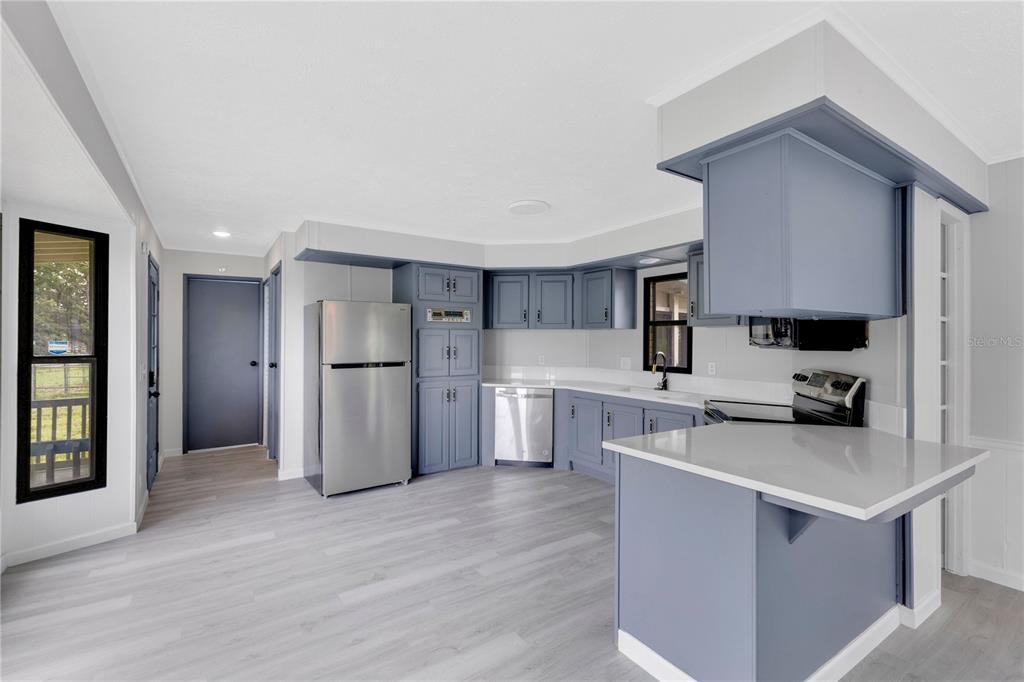 A kitchen with blue cabinets, stainless steel appliances, and light wood-look flooring — 9185 CONCORD ROAD, ST CLOUD, FL