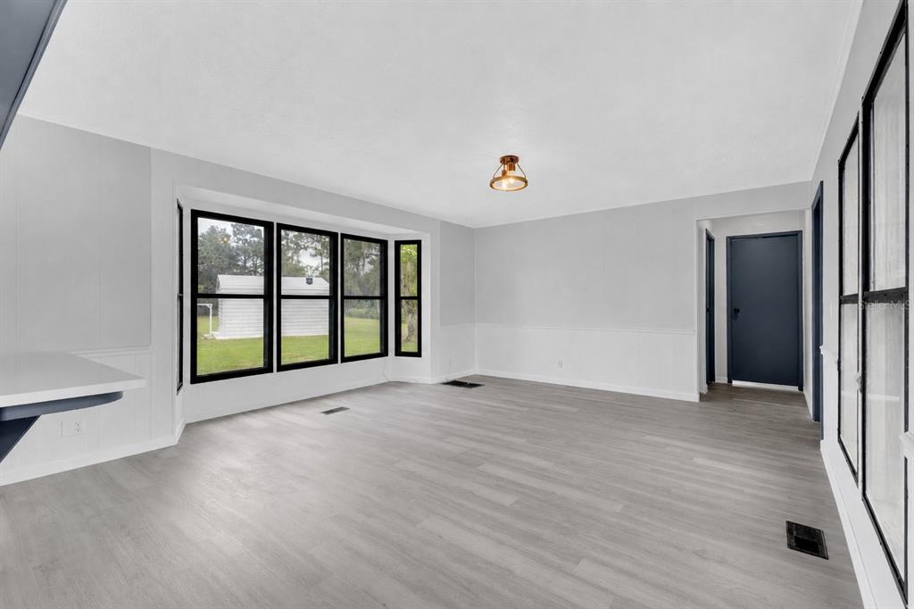 An empty room with gray wood-look flooring, white walls, and a large bay window — 9185 CONCORD ROAD, ST CLOUD, FL