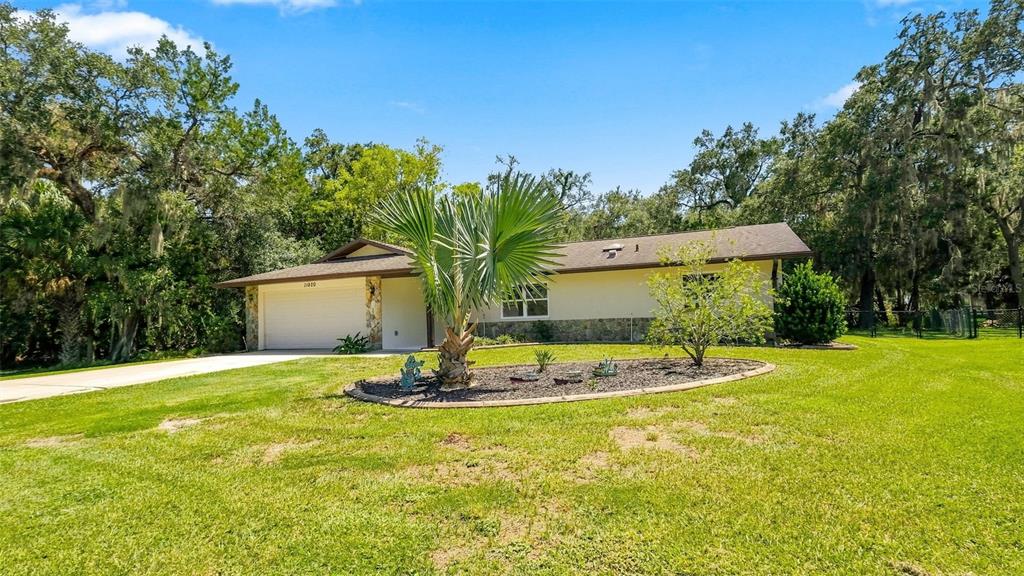 A single-story house with a stone facade, a two-car garage, and a palm tree landscaping — 11820 W FISHERMAN LANE, HOMOSASSA, FL