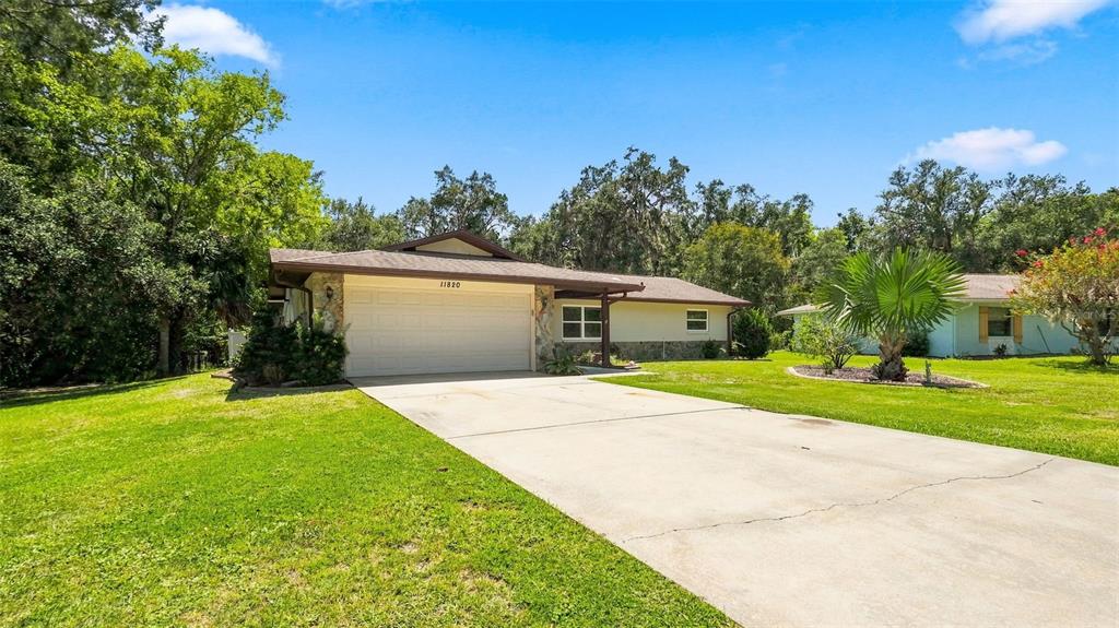 A single-story house with a two-car garage, stone accents, and a concrete driveway — 11820 W FISHERMAN LANE, HOMOSASSA, FL