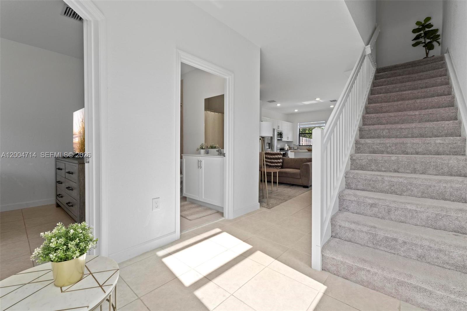 An entryway features a carpeted staircase, a tiled floor, and views into a bathroom and kitchen — 20655 NE 7th Pl, Miami FL 33179, MIAMI, FL