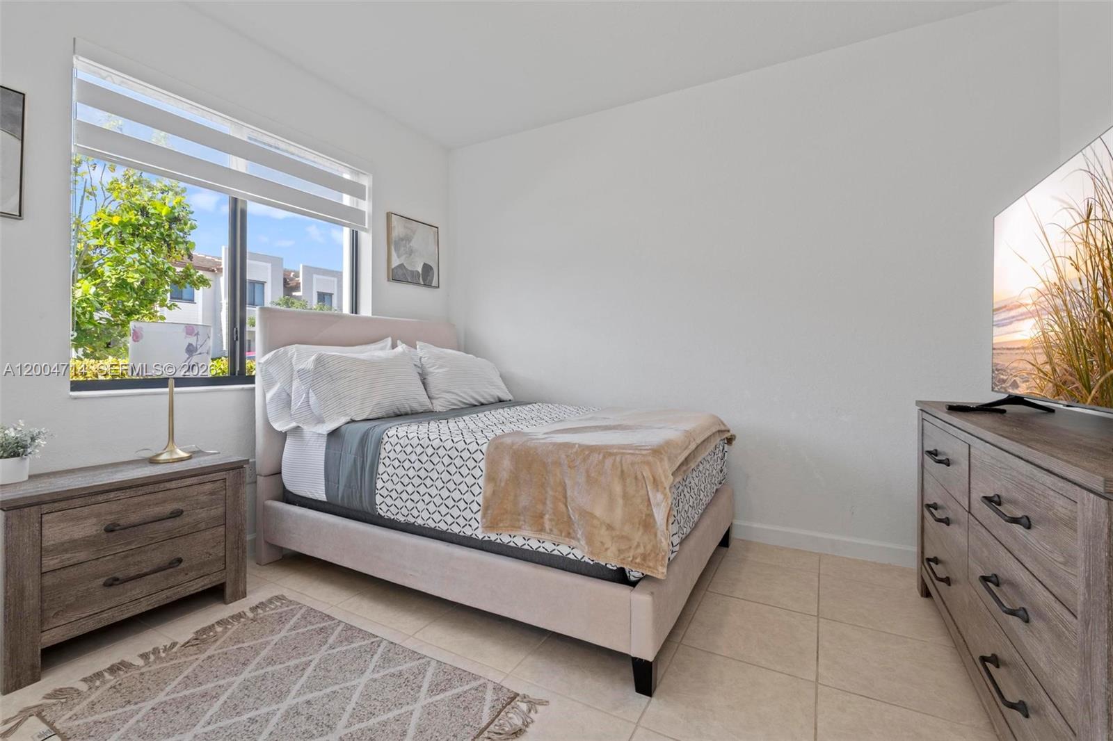 A bedroom features a bed, a dresser with a television, and a window with blinds — 20655 NE 7th Pl, Miami FL 33179, MIAMI, FL