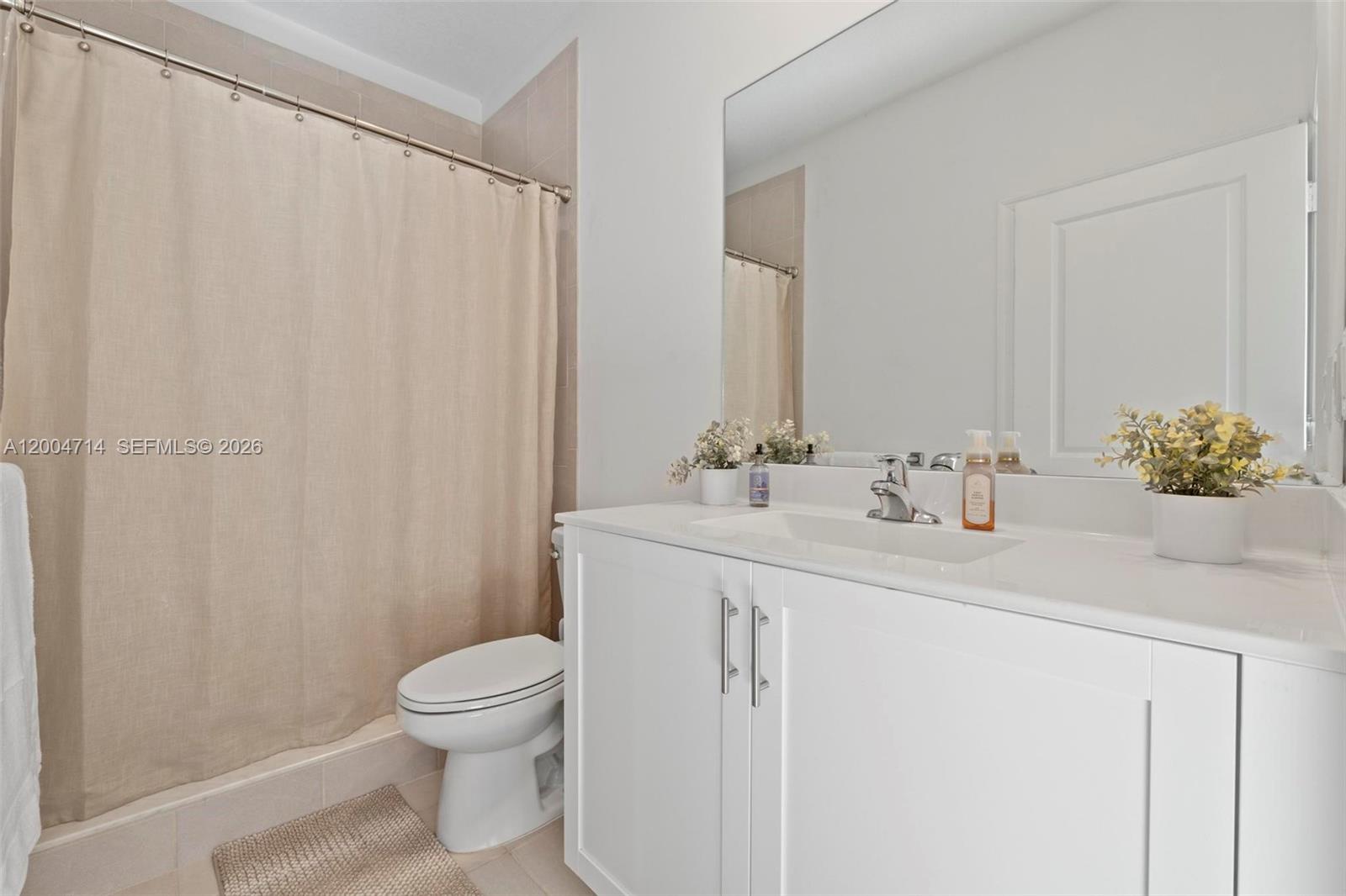 A bathroom features a white vanity, a toilet, and a shower with a beige curtain — 20655 NE 7th Pl, Miami FL 33179, MIAMI, FL