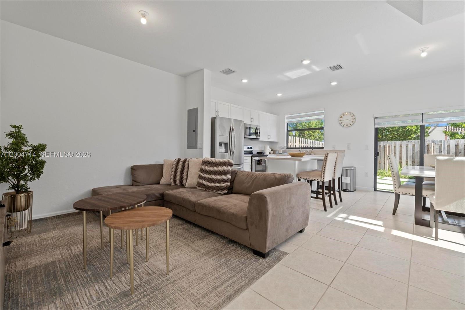 An open-concept living and dining area features a brown sectional sofa and tile flooring — 20655 NE 7th Pl, Miami FL 33179, MIAMI, FL