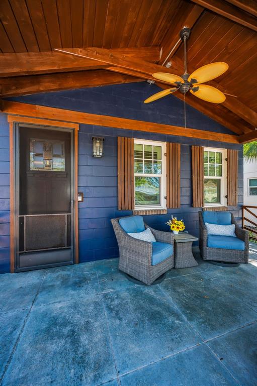 A covered porch features blue block walls, a wood ceiling, and two wicker armchairs — 525 LEXINGTON STREET, DUNEDIN, FL