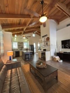 A living room with wood-paneled ceilings, a leather sofa, and an open kitchen beyond — 525 LEXINGTON STREET, DUNEDIN, FL