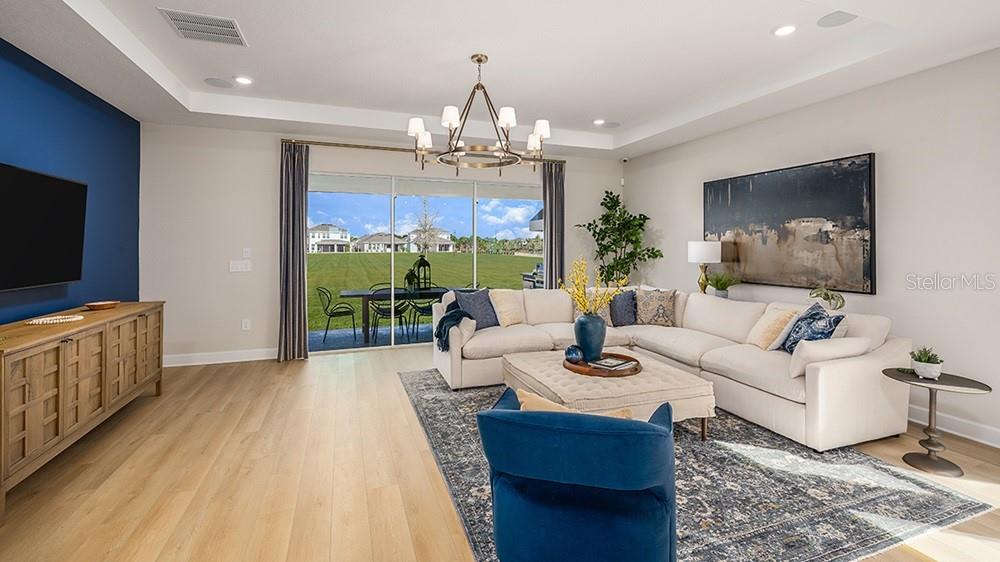 A living room features a blue accent wall, a sectional sofa, and a sliding glass door — 12711 DOCKYARD TRAIL, PALMETTO, FL