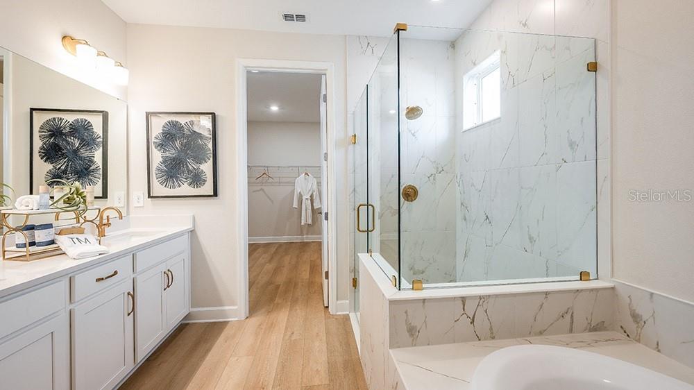 A bathroom features a white vanity, a glass-enclosed shower with marble tile, and wood flooring — 12711 DOCKYARD TRAIL, PALMETTO, FL