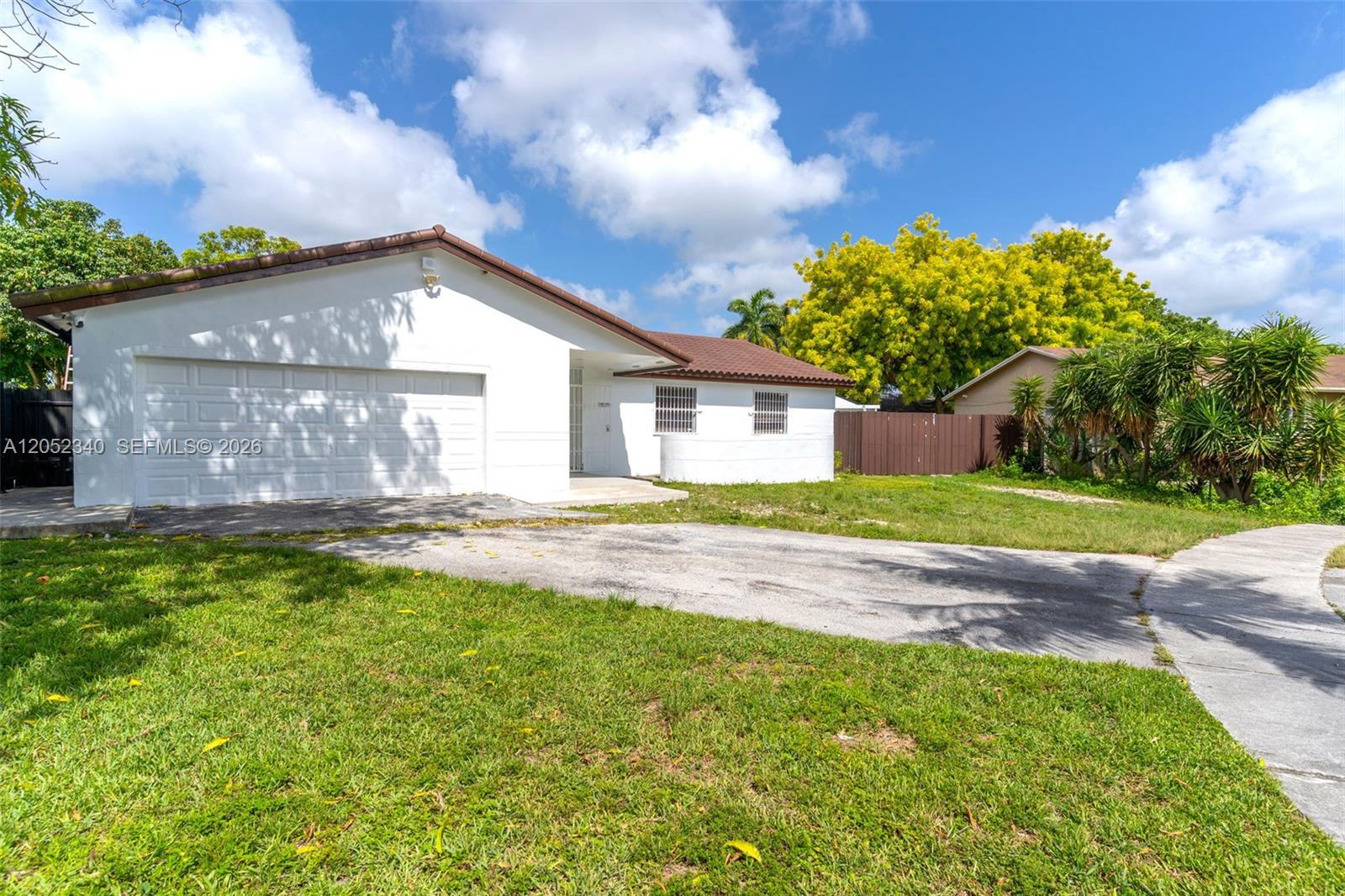 A white single-story house with a brown roof and a concrete driveway — 26222 SW 133rd Ct, Homestead FL 33032, HOMESTEAD, FL