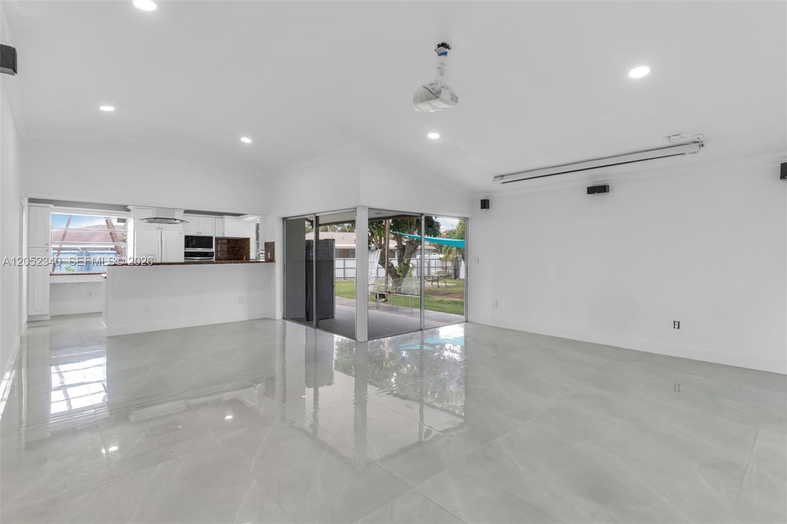 A bright, open-concept living area features polished tile floors, recessed lighting, and sliding glass doors — 26222 SW 133rd Ct, Homestead FL 33032, HOMESTEAD, FL