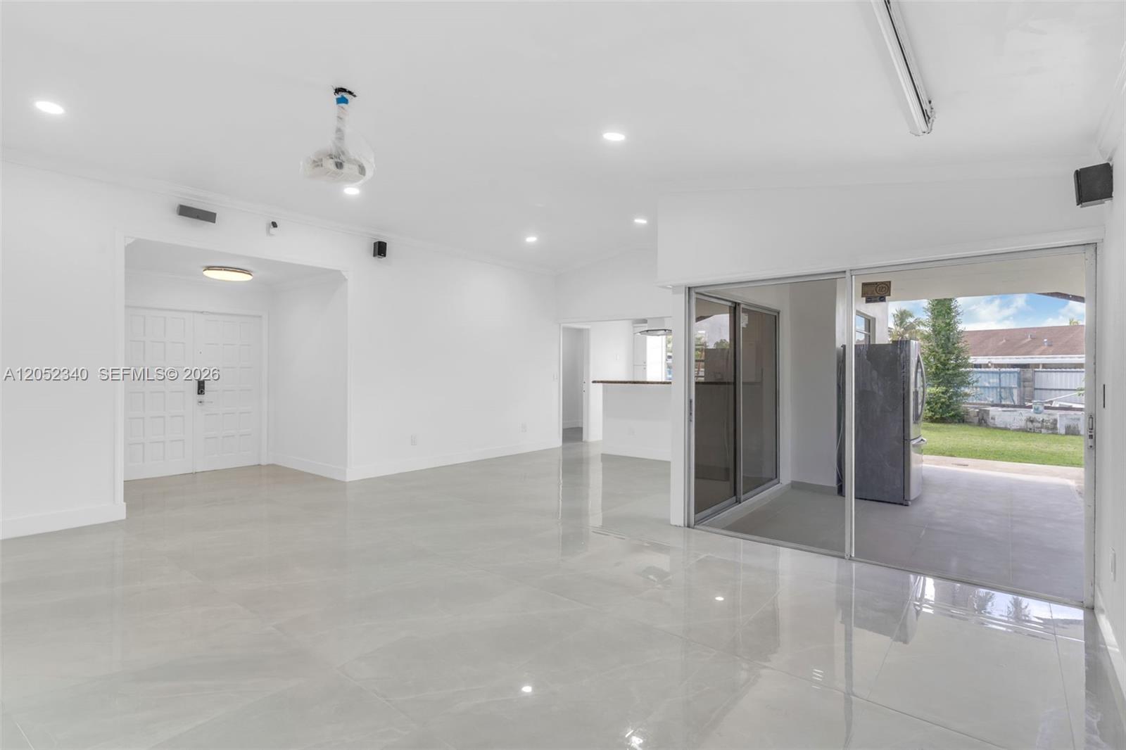 A bright, open-concept living area features white walls, glossy tile floors, and sliding glass doors — 26222 SW 133rd Ct, Homestead FL 33032, HOMESTEAD, FL