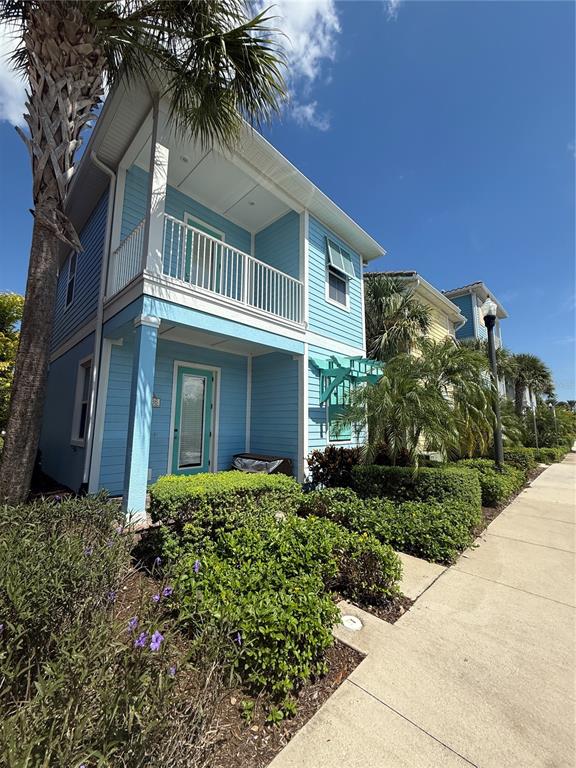 A two-story blue house with a front porch and balcony sits beside a sidewalk — 2986 SALTED RIM ROAD, KISSIMMEE, FL