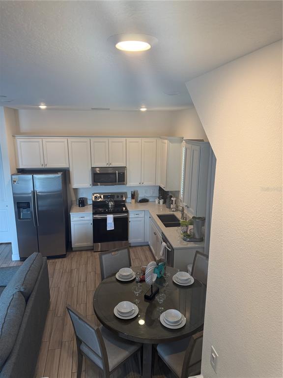 A kitchen with white cabinets, stainless steel appliances, and a round dining table — 2986 SALTED RIM ROAD, KISSIMMEE, FL