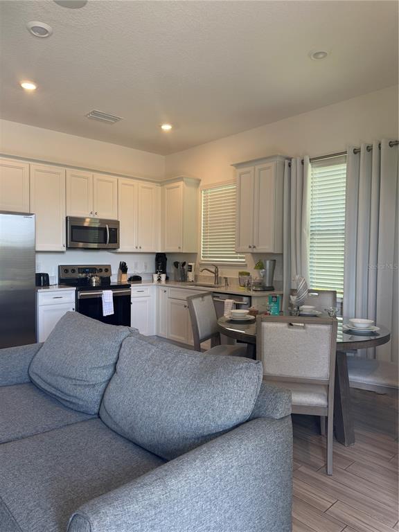 A kitchen with white cabinets and stainless steel appliances sits beside a dining area — 2986 SALTED RIM ROAD, KISSIMMEE, FL