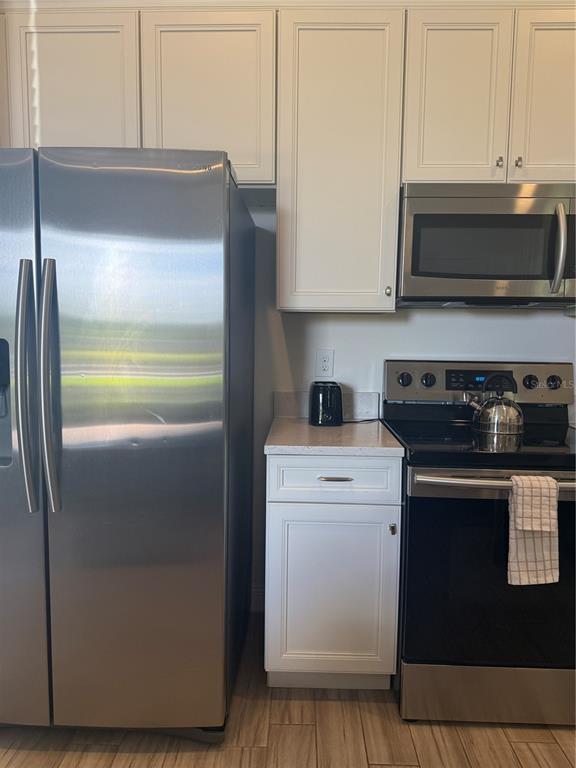 A kitchen features white cabinets, stainless steel appliances, and a small counter between the units — 2986 SALTED RIM ROAD, KISSIMMEE, FL