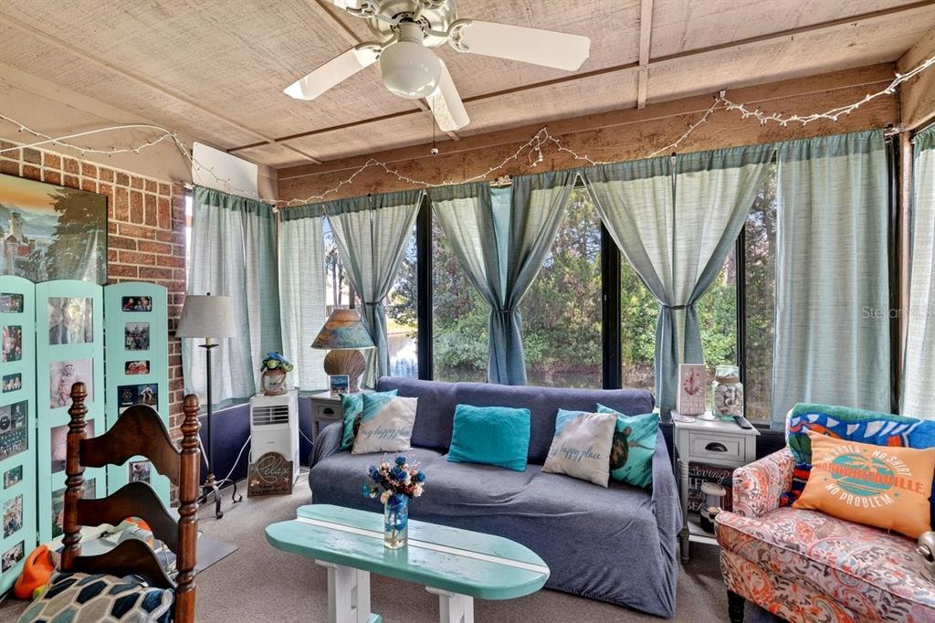 A sunroom features a sofa, patterned armchair, light blue coffee table, and large windows — 188 GRAY DOVE COURT, DAYTONA BEACH, FL