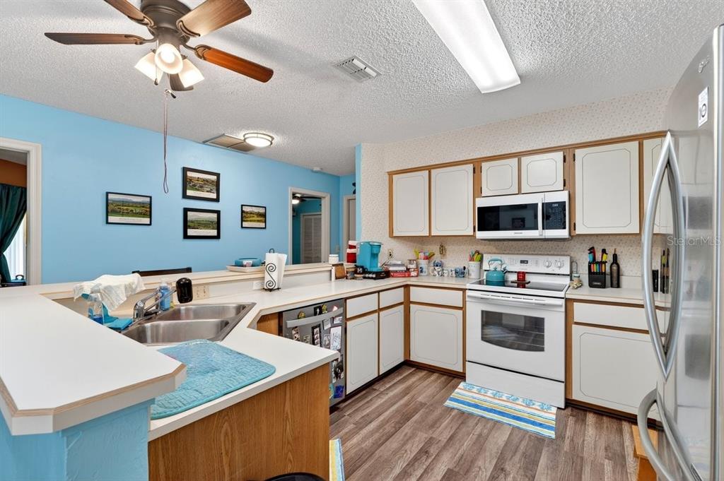 A kitchen with white cabinets, light countertops, blue walls, and wood-look flooring — 188 GRAY DOVE COURT, DAYTONA BEACH, FL