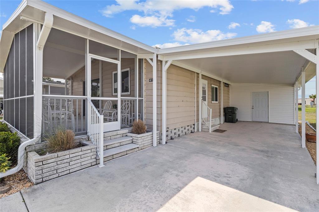 A manufactured home exterior features a screened-in porch, a concrete driveway, and a covered carport — 611 LA JOLLA CIRCLE, NORTH PORT, FL