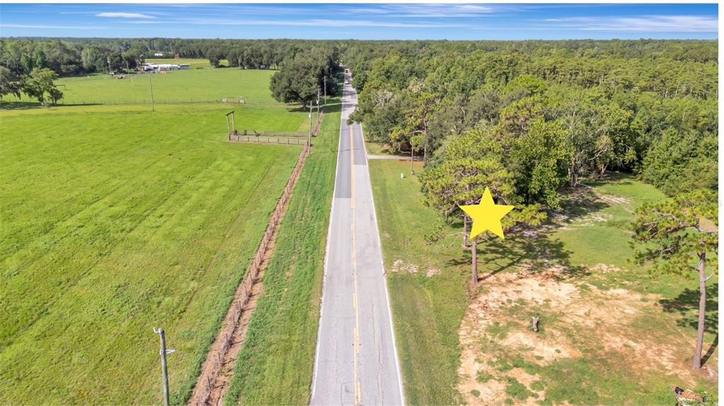 An aerial view shows a paved road running between a large grassy field and trees — 4541 COUNTY ROAD 561, CLERMONT, FL