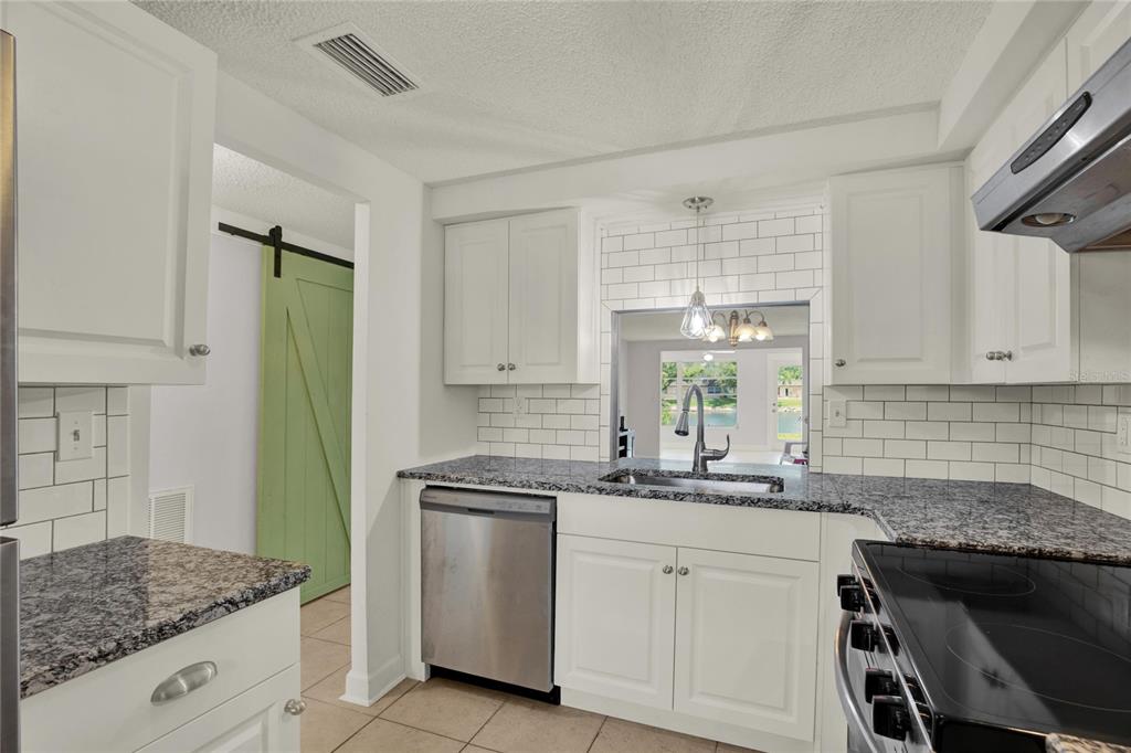 A kitchen with white cabinets, granite countertops, subway tile backsplash, and stainless steel appliances — 4115 HAMPTON DRIVE UNIT n/a, NEW PORT RICHEY, FL