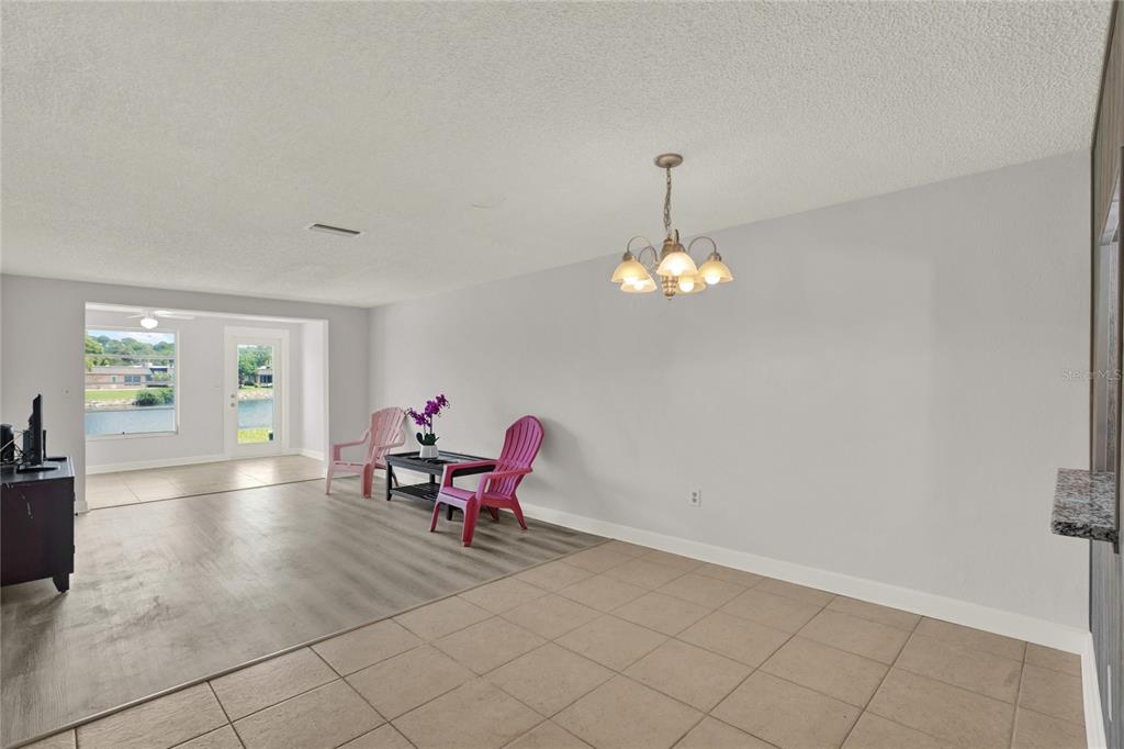 A dining area with tile flooring, a chandelier, and a view of a lake outside — 4115 HAMPTON DRIVE UNIT n/a, NEW PORT RICHEY, FL