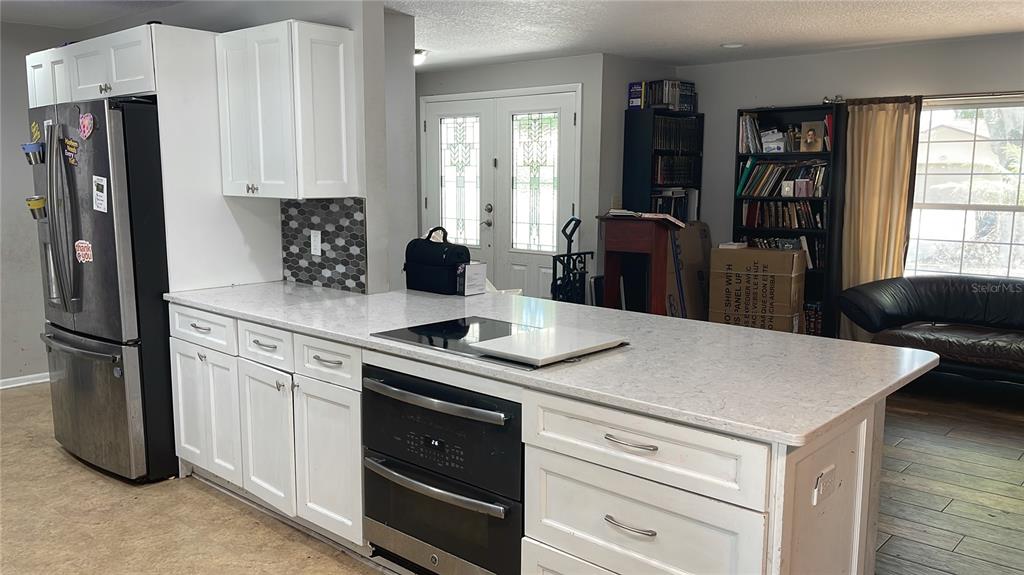 A kitchen features white cabinets, a light-colored countertop, a black oven, and a refrigerator — 8537 TANSY DRIVE, ORLANDO, FL