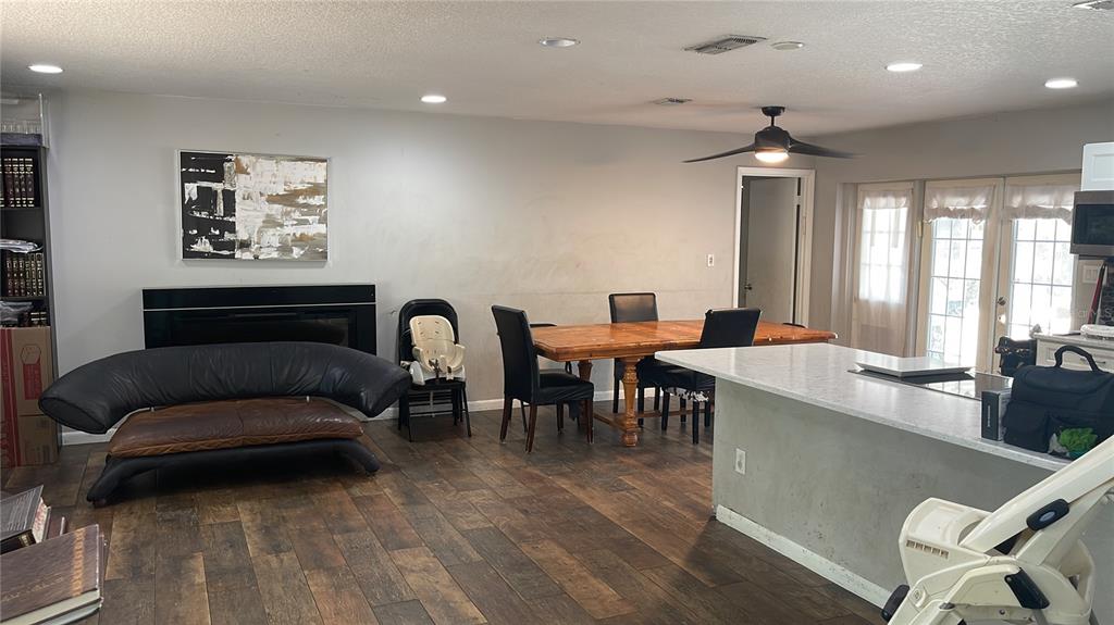 A dining area and living space feature wood-look flooring, a fireplace, and a kitchen island — 8537 TANSY DRIVE, ORLANDO, FL