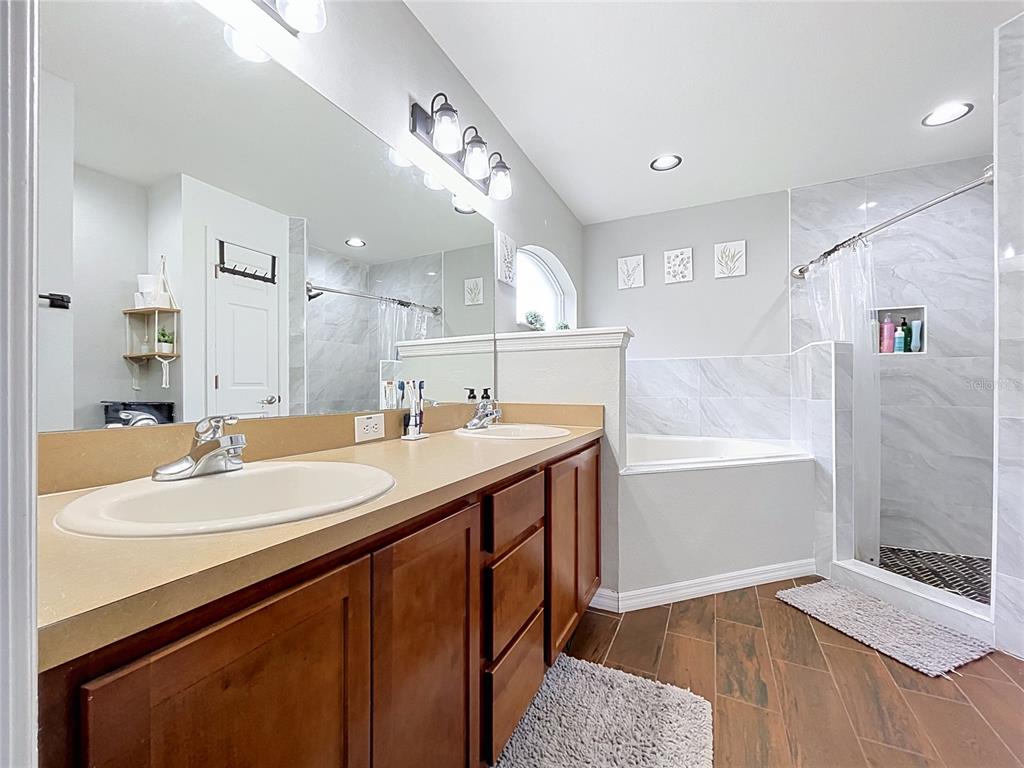 A bathroom features a double vanity with wood cabinets, a soaking tub, and a shower — 3217 ENCLAVE BOULEVARD, MULBERRY, FL