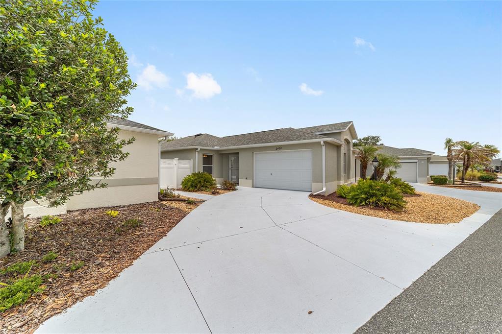 A single-story house with a white garage door and a concrete driveway — 2426 SAFFRON LANE, THE VILLAGES, FL