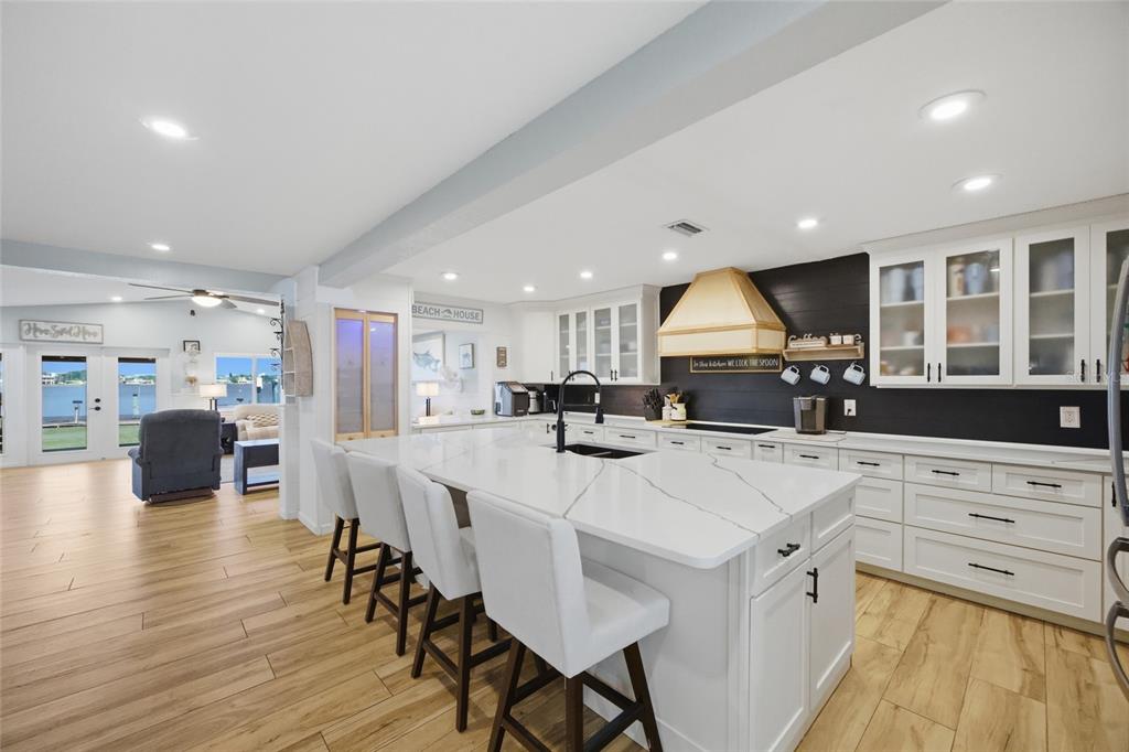 A modern kitchen features a large white quartz island, white cabinetry, and dark wood flooring — 8211 HAYWARD LANE, PORT RICHEY, FL