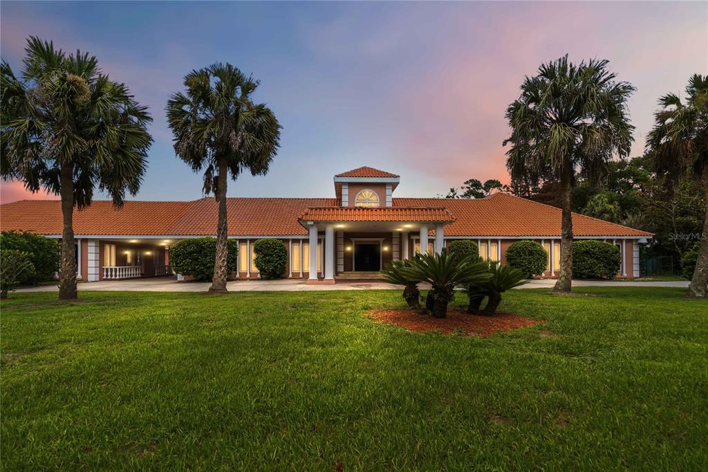 A single-story house with a terracotta tile roof and a columned entrance at dusk — 593 DUNMAR CIRCLE, WINTER SPRINGS, FL