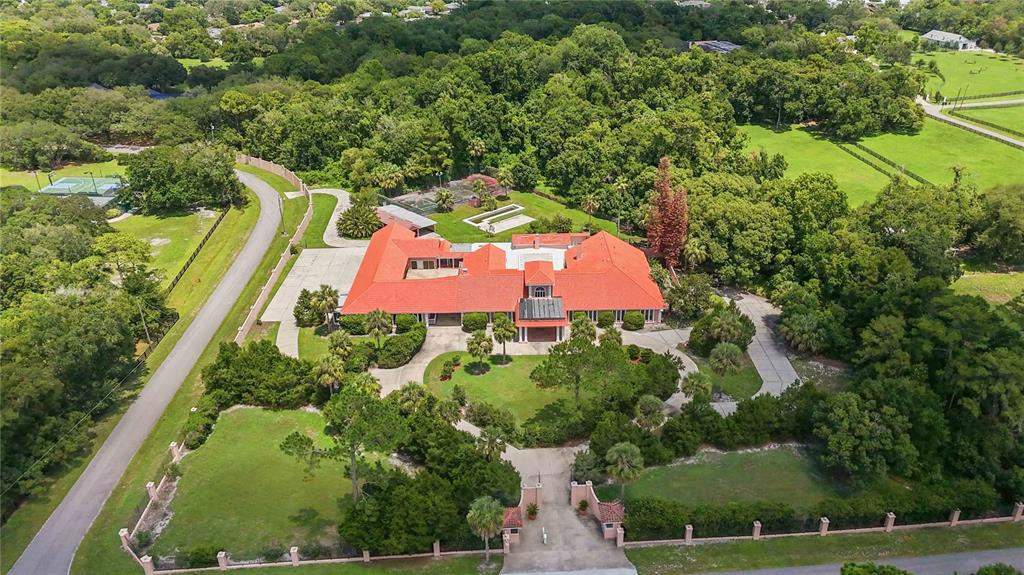An aerial view shows a large house with a red tile roof and gated driveway — 593 DUNMAR CIRCLE, WINTER SPRINGS, FL