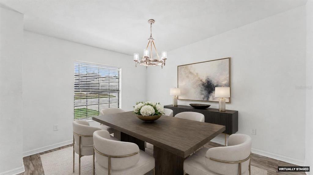 This virtually staged dining room features a wooden table, upholstered chairs, and a chandelier — 2728 HUDSON STREET, LAKELAND, FL