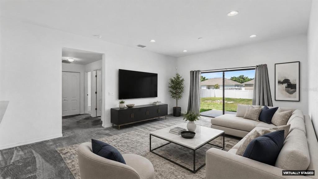 A living room with a large sectional sofa, television, and sliding glass doors to a yard — 2728 HUDSON STREET, LAKELAND, FL