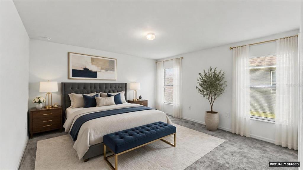 A virtually staged bedroom features a tufted gray headboard, blue accents, and two windows — 2728 HUDSON STREET, LAKELAND, FL