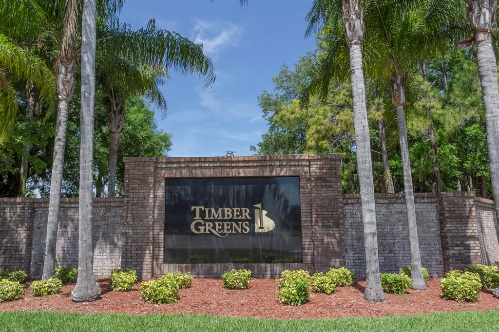 An open-concept living and dining area features light-colored furniture, hardwood floors, and a kitchen — 10029 BROOKDALE DRIVE, NEW PORT RICHEY, FL
