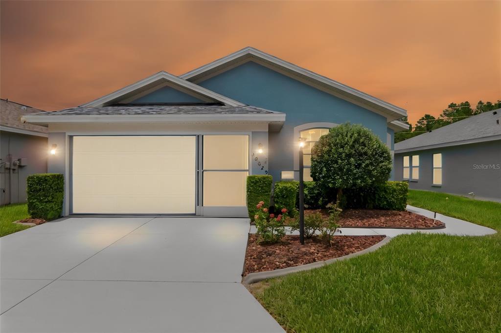 A spacious living area with beige carpeting, vaulted ceilings, and an adjacent kitchen with light cabinets — 10029 BROOKDALE DRIVE, NEW PORT RICHEY, FL