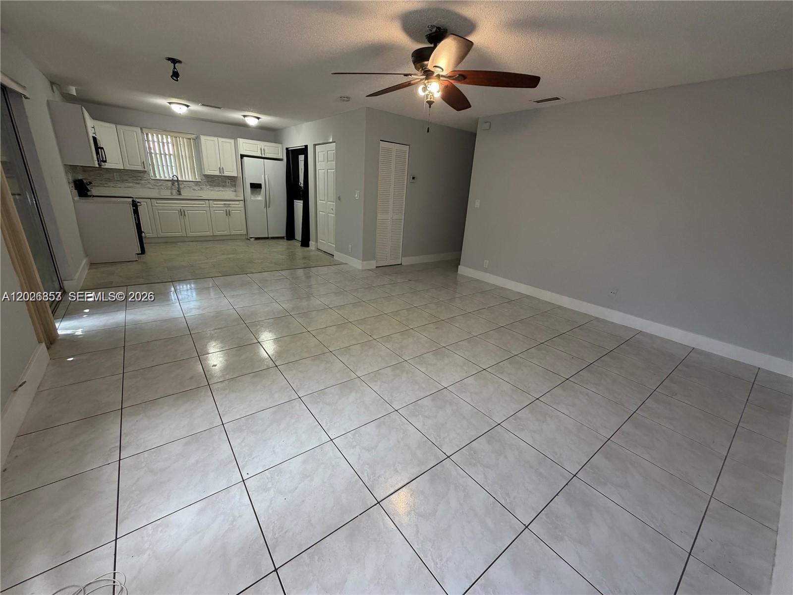 An open-concept living area features light-colored tile flooring, a ceiling fan, and a white kitchen — 6316 Lincoln St, Hollywood FL 33024, HOLLYWOOD, FL