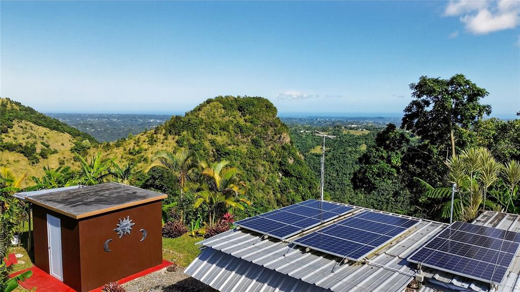 A small brown building stands next to a metal roof with several solar panels installed — ALTURITAS CACAO PARCEL B, OROCOVIS, PR