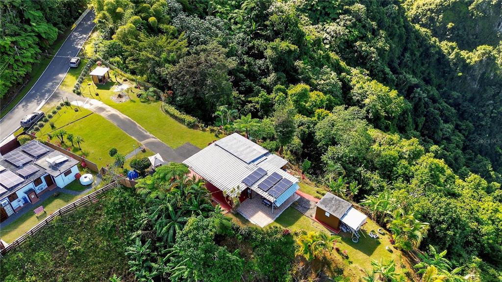 An aerial view shows two houses with solar panels on a lush, forested hillside — ALTURITAS CACAO PARCEL B, OROCOVIS, PR