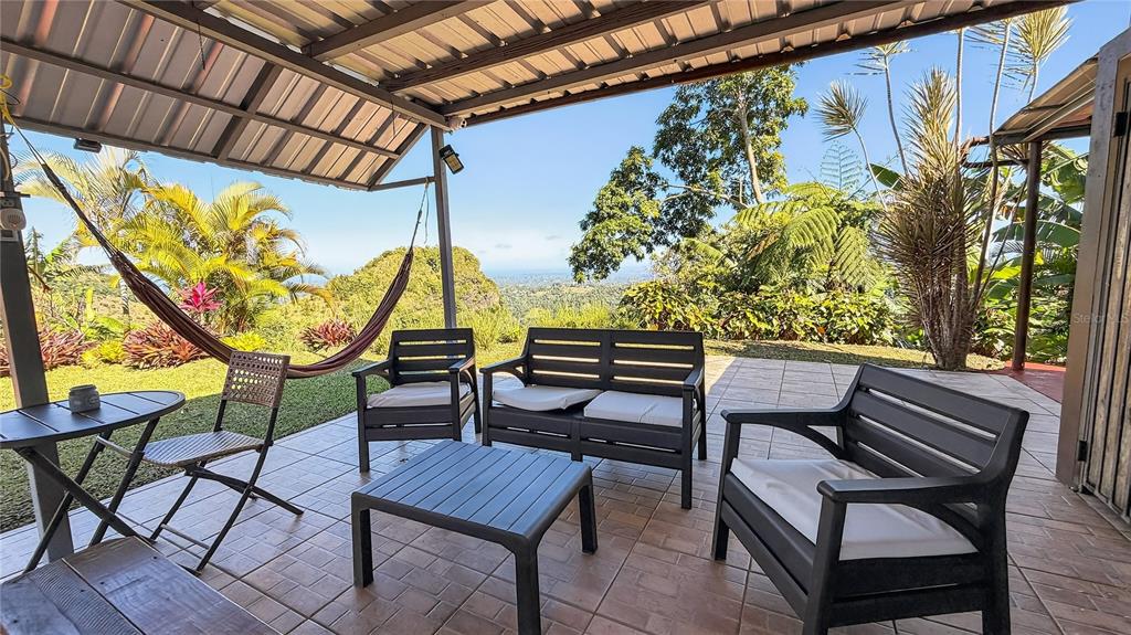 A covered patio features outdoor furniture, a hammock, and a scenic view of the landscape — ALTURITAS CACAO PARCEL B, OROCOVIS, PR
