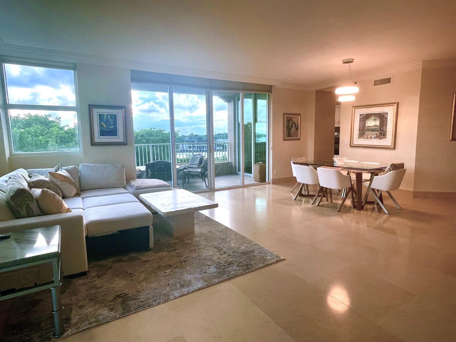 A spacious living and dining area with light tile floors, a sectional sofa, and balcony access — 3720 S Ocean Boulevard # 301b, Highland Beach FL 33487, HIGHLAND BEACH, FL