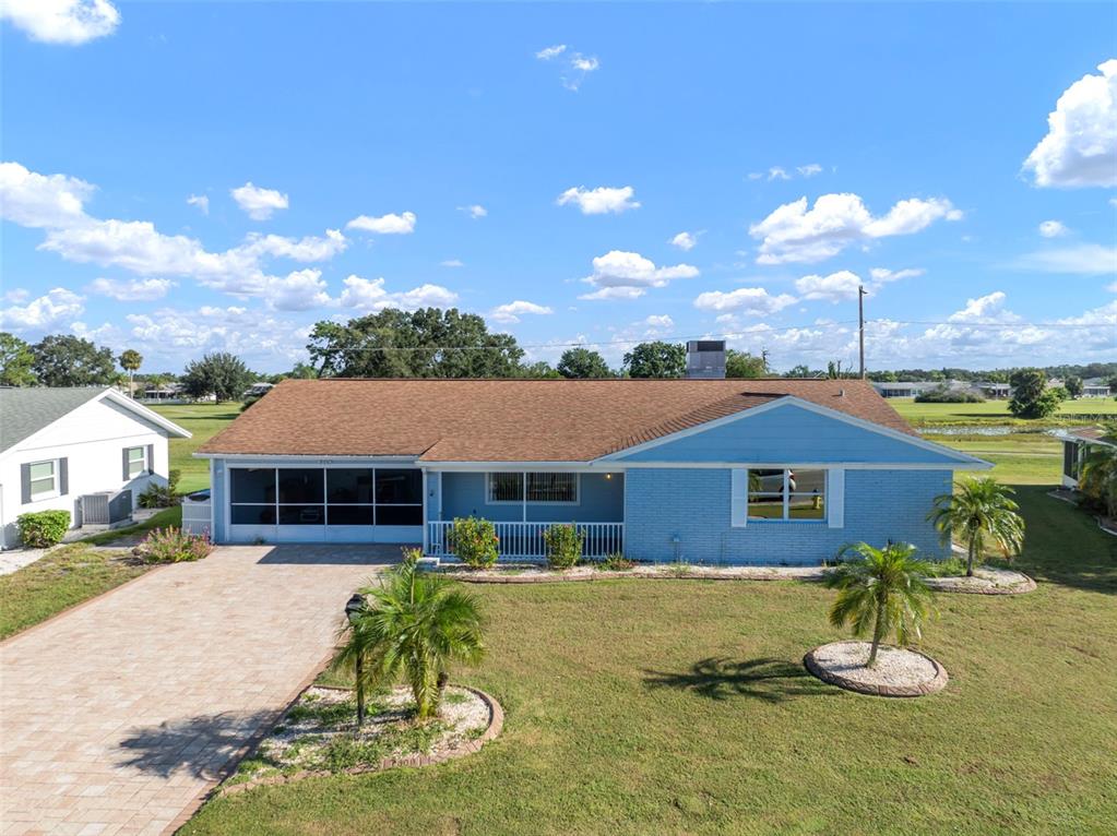 A light blue, single-story house with a brown shingled roof and a paved driveway — 609 FOX HILLS DRIVE, SUN CITY CENTER, FL